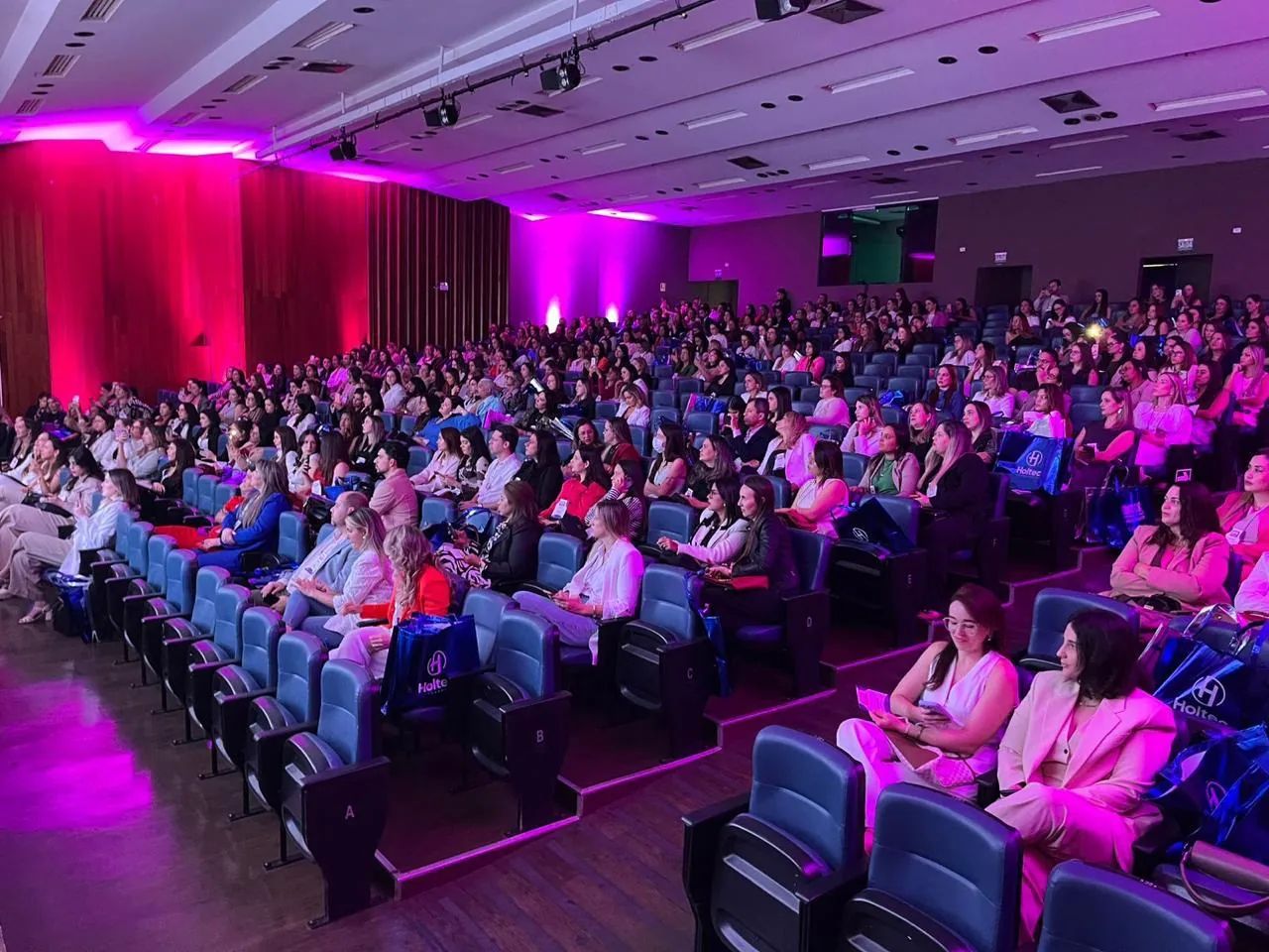 Público do Contox sob a iluminação magenta do palco